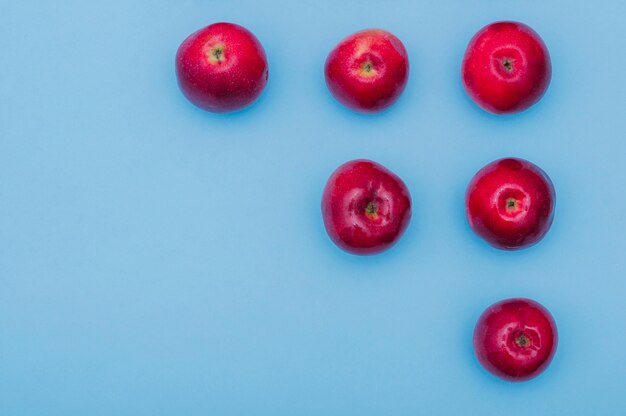 Increasing row of red fresh apples on blue background