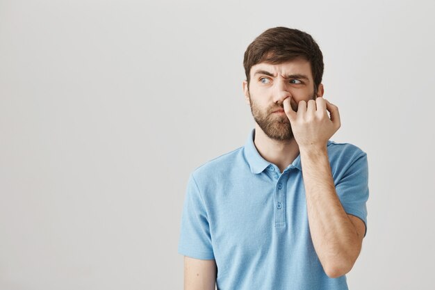 Indecisive young bearded man posing