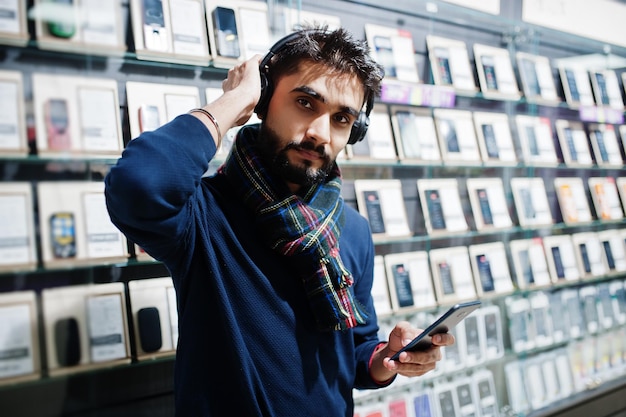 Free photo indian beard man customer buyer at mobile phone store listen music from wireless earphones connect to his smartphone south asian peoples and technologies concept cellphone shop