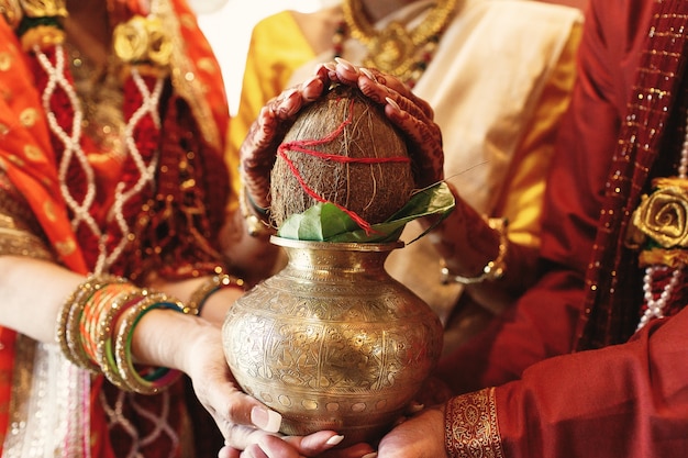 Free photo indian bride's parents hold a bowl with coconut under her hands