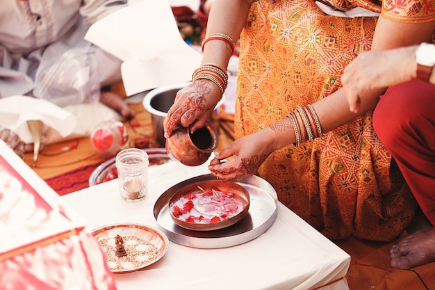 Free photo indian bride washes nuts over the plate with species and petals