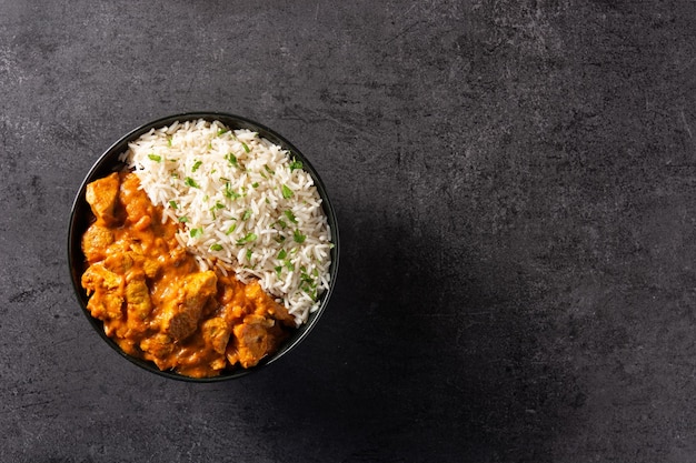 Free photo indian butter chicken in black bowl on black background