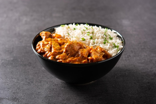 Indian butter chicken in black bowl on black background