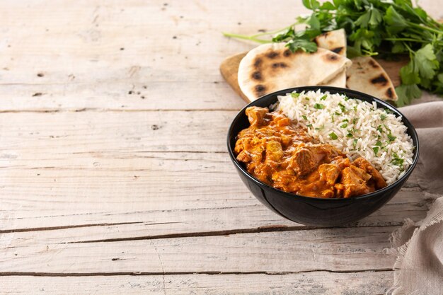 Indian butter chicken in black bowl on wooden table