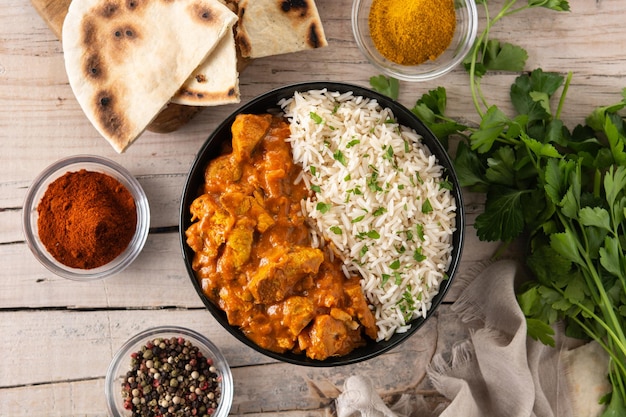 Indian butter chicken in black bowl on wooden table