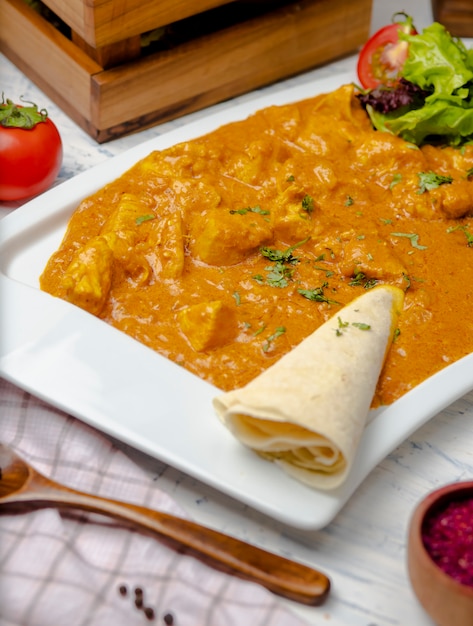 Free photo indian curry with chicken breast and tomato sauce served with lavash.