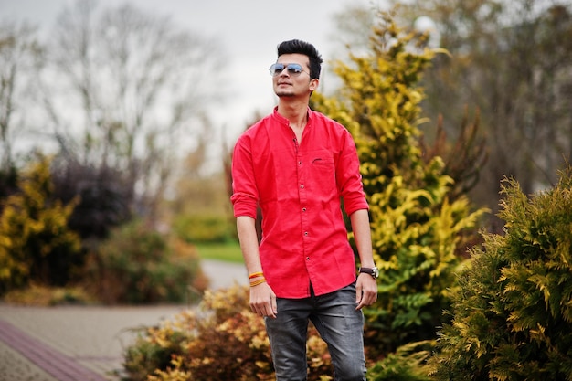 Indian man at red shirt and sunglasses posed outdoor