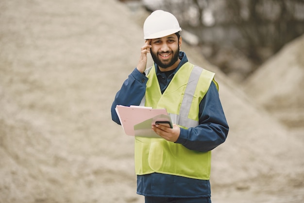 Free Photo indian man working. male in a yellow vest. man with folder.