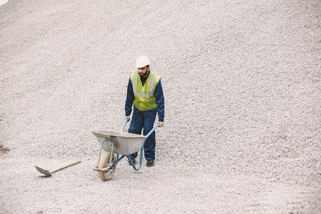 Free photo indian man working. male in a yellow vest. man with wheelbarrow.