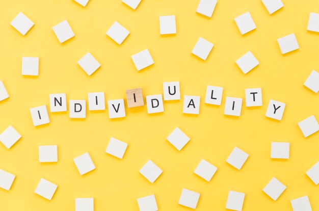 Individuality lettering made with wooden cubes on yellow background