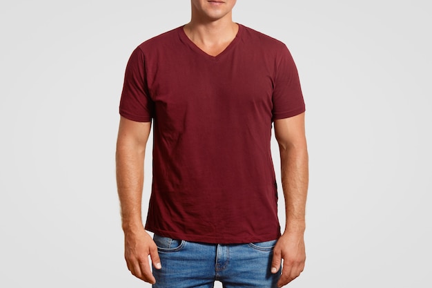 Indoor cropped image of muscular young man in red t shirt and jeans