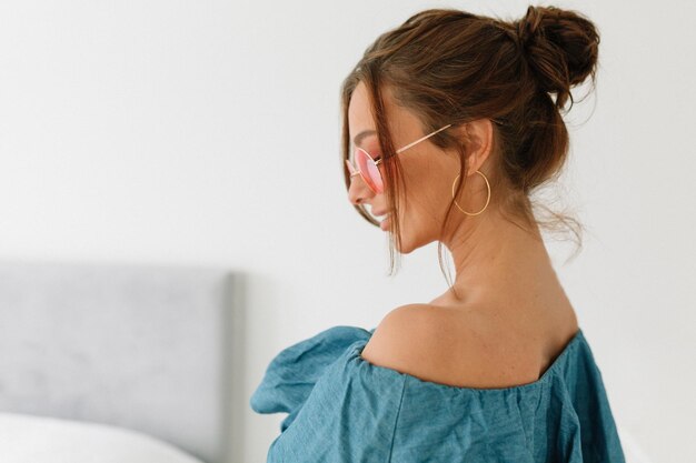 Indoor shot of european pretty woman with dark hair wearing blue tshirt looking down and standing over isolated background