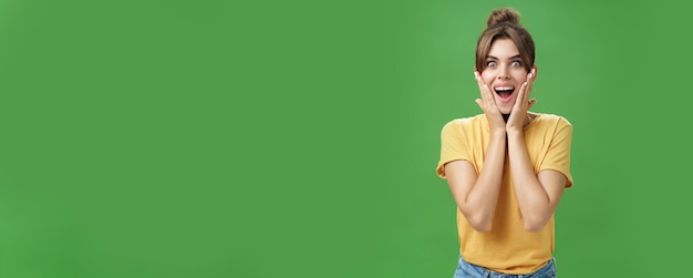 Free photo indoor shot of excited and surprised energized attractive glamorous female in yellow tshirt touching