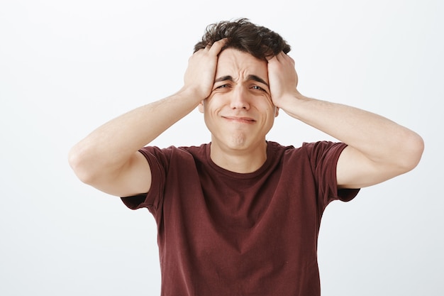 Indoor shot of miserable desparate gloomy guy in casual outfit