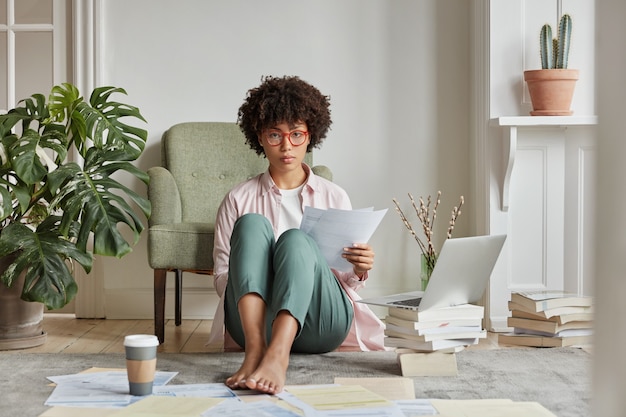 Indoor view of intelligent woman posing in cozy apartment