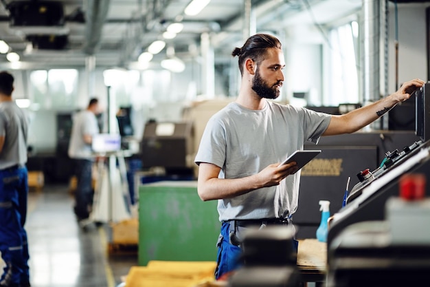 Free photo industrial engineer using touchpad while operating a cnc machine in a factory