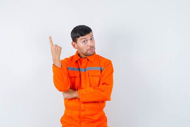 Free photo industrial man pointing up in uniform and looking hesitant. front view.