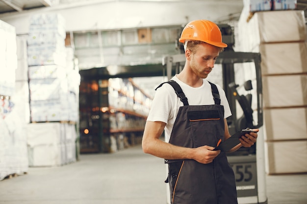 Free photo industrial worker indoors in factory. young technician with orange hard hat.