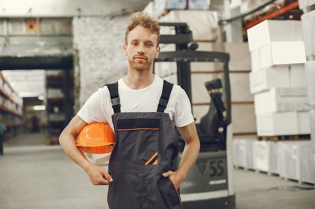 Free photo industrial worker indoors in factory. young technician with orange hard hat.