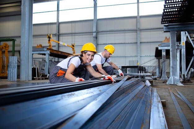 Industrial workers working in factory hall with metal