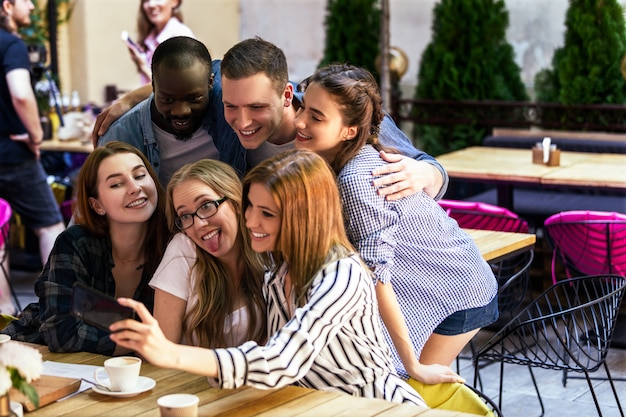 Informal meeting of best friends in the cosy cafe and taking selfie photo on the smartphone