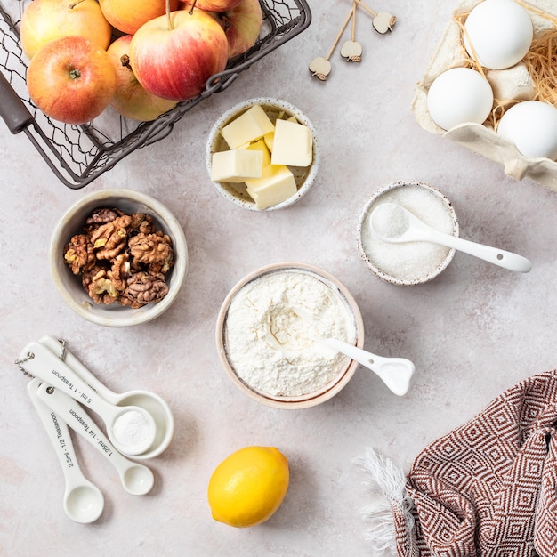 Ingredients for a sweet apple pie on a stone light background View from above