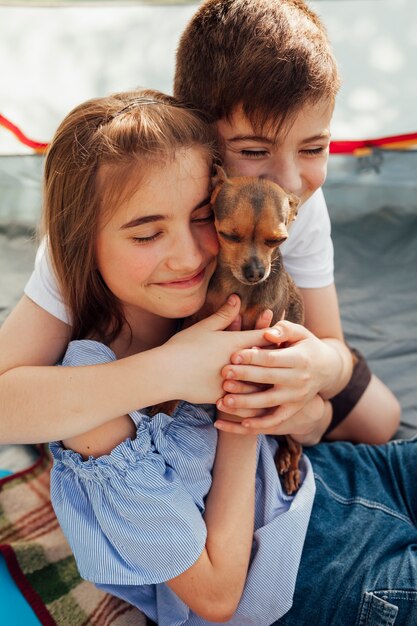 Innocent smiling sibling loving their pet in tent