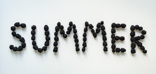 Inscription Summer made with blackberries on white surface