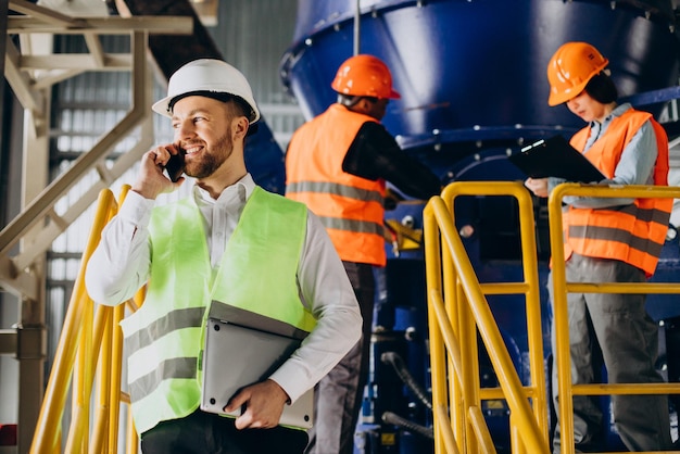 Free photo inspector at a factory talking on the phone while others are working