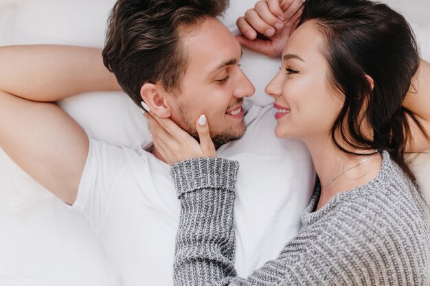 Inspired caucasian woman smiling while holding husband's face in hands