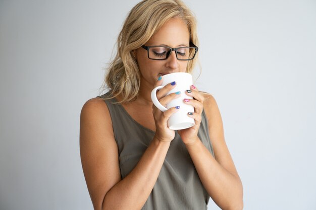 Inspired female office worker enjoying coffee break.