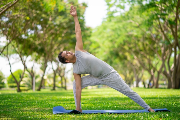 Inspired Indian man doing yoga asanas in city park. Young citizen exercising outside 