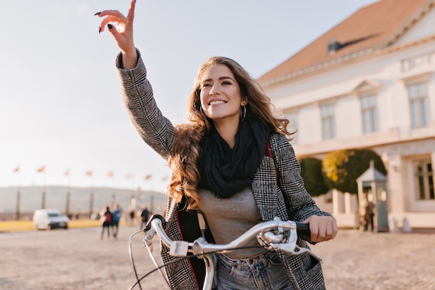 Free Photo inspired young woman in black scarf riding on bicycle around european town