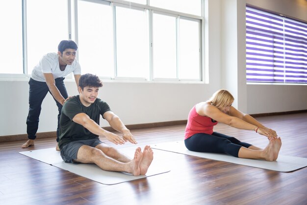 Instructor helping beginners to do forward bend pose