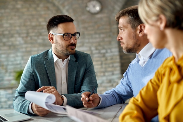 Free photo insurance agent having a meeting with a couple and offering them to sign an agreement in the office