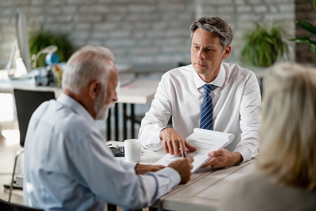 Free photo insurance agent having a meeting with senior clients and pointing at place of the signature on a contract