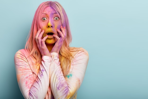 Free Photo intense shocked blonde european woman smeared with multicolored powder, gasps and opens mouth