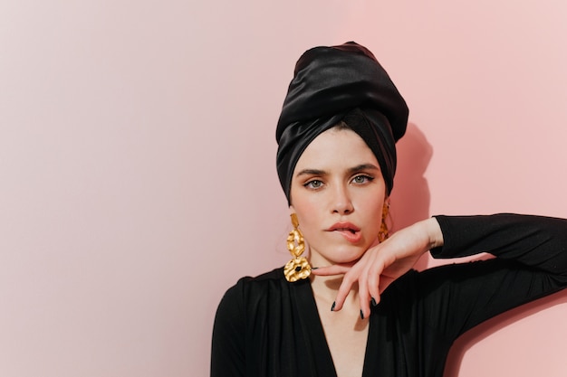 Interested woman in turban standing on light wall