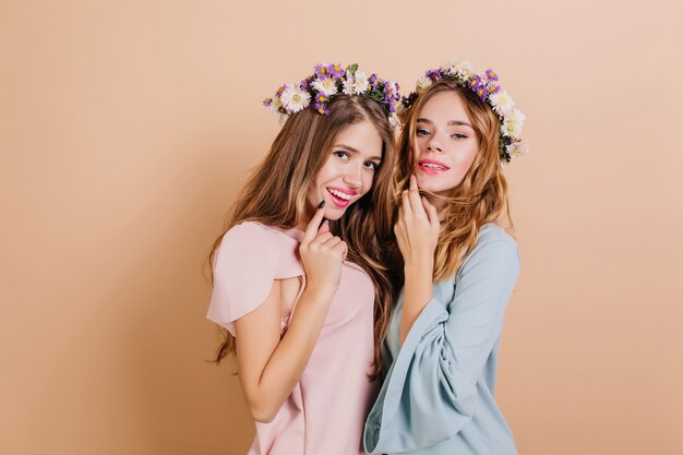 Interested woman with white and purple flowers in hair posing with sister