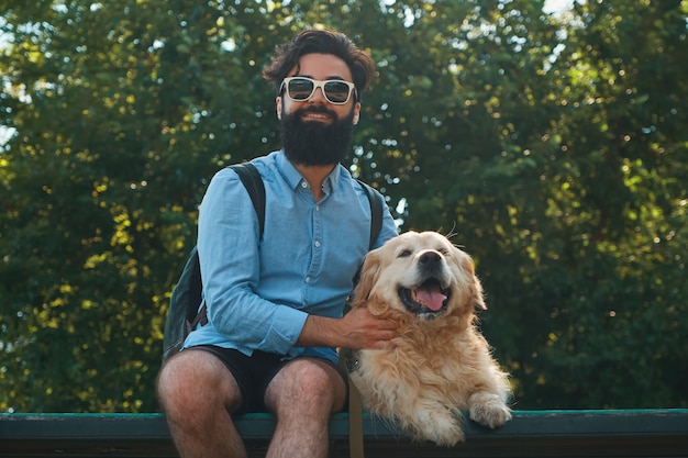 Interesting man sitting with his dog on the chair in the park