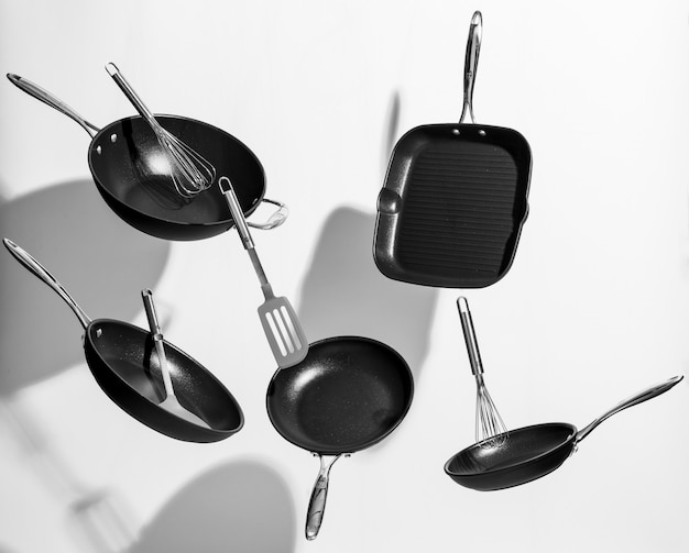 Free photo interesting shot of trendy black kitchen utensils dancing on white background