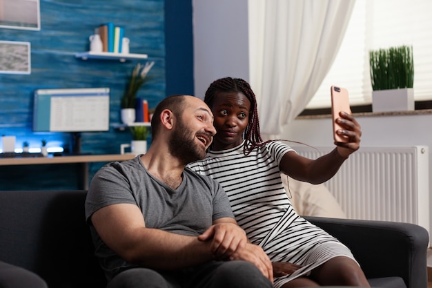 Interracial couple holding smartphone for pictures