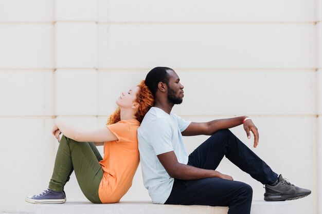 Interracial couple sitting back to back