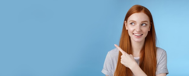 Free photo intrigued goodlooking redhead joyful curious girl watching looking upper left corner interested smiling broadly visit cool amusing place explore travelling new country astonished blue background