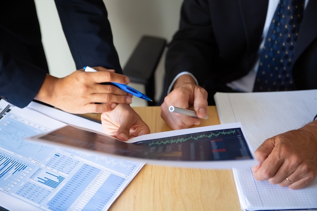 Free Photo investor and broker discussing trading strategy, holding papers with financial charts and pens. cropped shot. broker job or investment concept