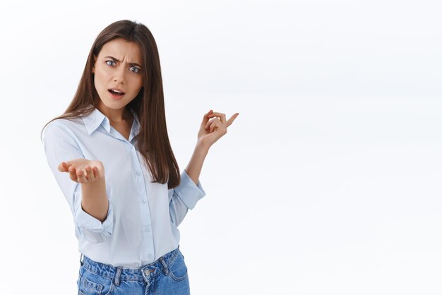 Irritated young businesswoman pointing at chart and scolding emplpoyee making mistake frowning disappointed demand answer on question what is this stand white background