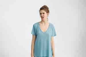 Free photo irritated young woman with grumpy expression, showing tongue while being dissatisfied with something. attractive female showing her disagreement isolated. negative emotions