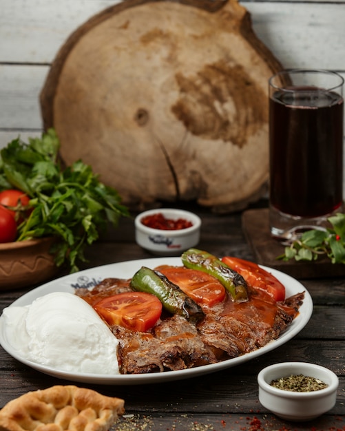 Free photo iskender kebab garnished with tomato sauce, pepper, served with yoghurt