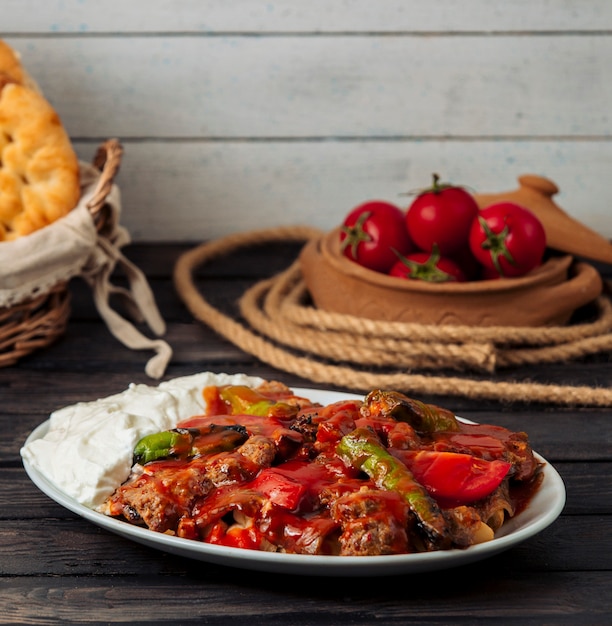 Free photo iskender kebab garnished with tomato sauce, served with yoghurt