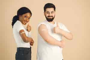 Free photo isolated, beige background. african woman and man showing thumbs up. vaccination against covid.